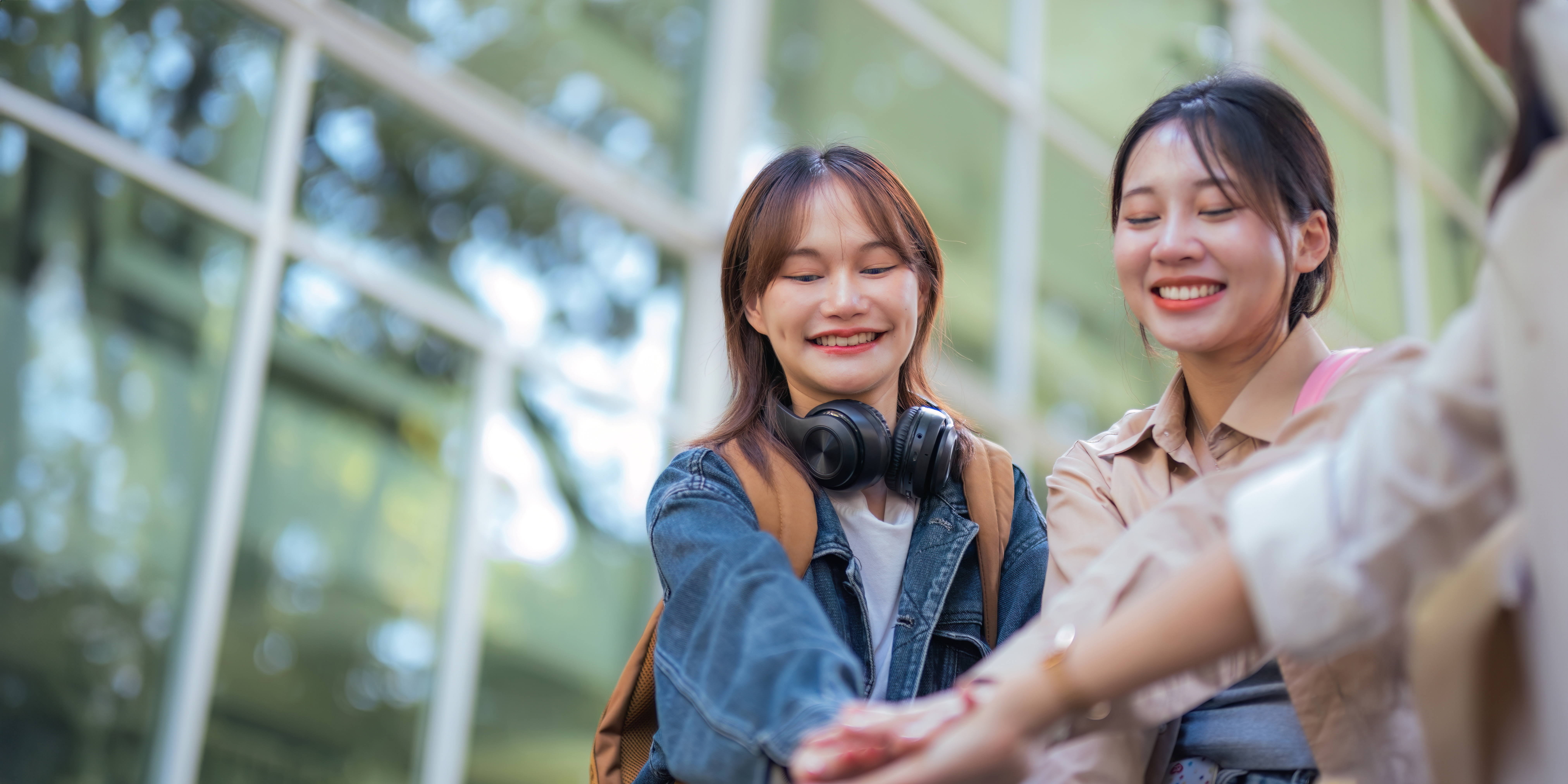 Happy females university student chat holding hands sincerely with each other after class. guy and girls wear casual clothes to university study. university College and University life concept