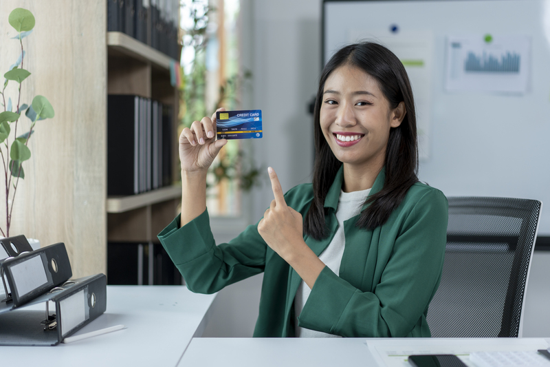 A woman is holding a credit card and smiling